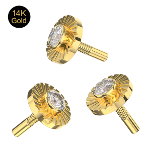 Close-up of the sunburst laser-cut texture on a 14K solid gold button piercing attachment with bezel-set CZ.